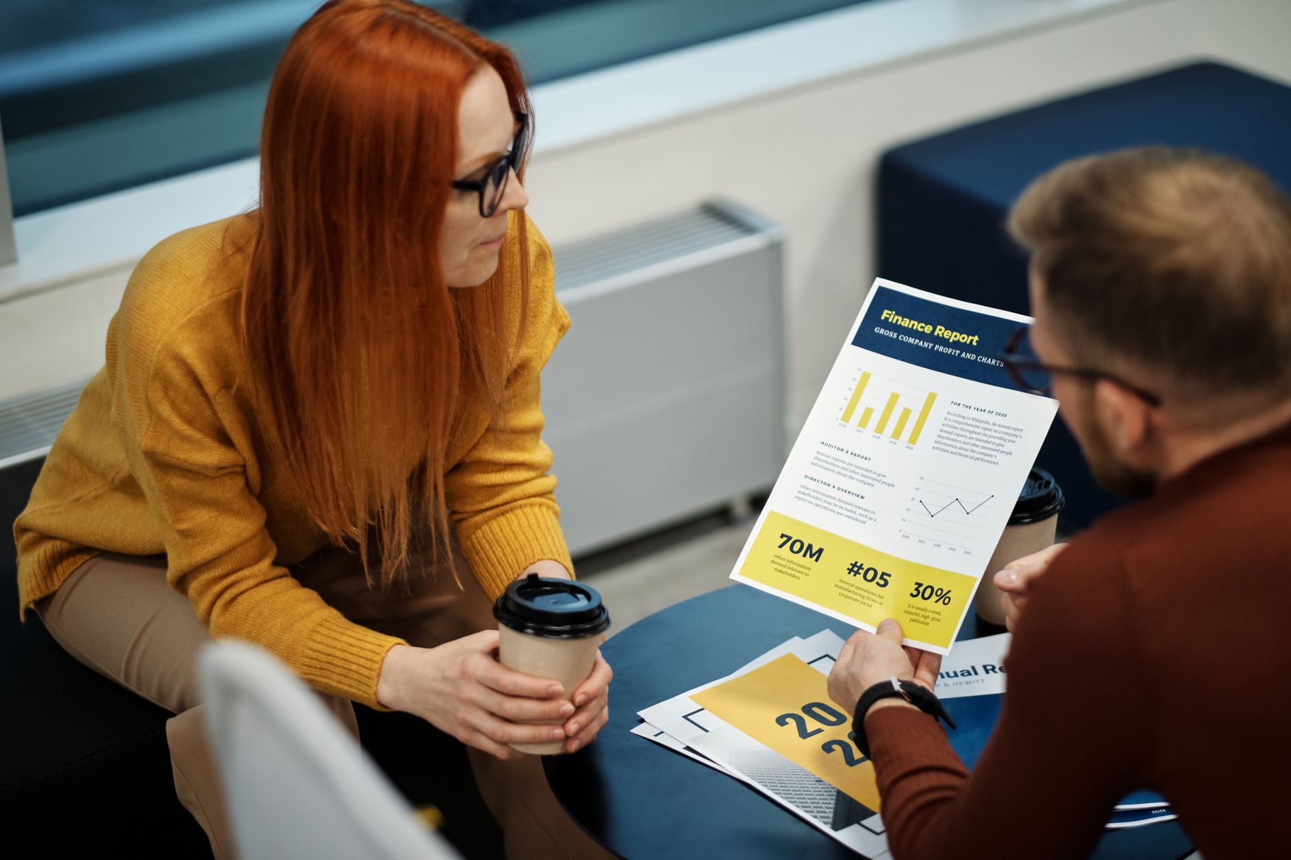 To personer gennemgår en trykt rapport ved et bord